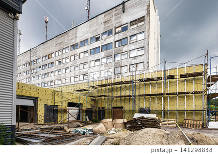 Workers are applying mineral wool insulation to the exterior of an office building. Scaffolding surrounds the structure as reconstruction takes place Workers are applying mineral wool insulation to the exterior of an office building. Scaffolding surrounds the structure as reconstruction takes place 141298838
