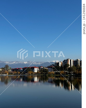 Bright morning reflection of Batumi skyline on Nurigeli Lake in Georgia with snow-capped Caucasus Mountains in the background Bright morning reflection of Batumi skyline on Nurigeli Lake in Georgia with snow-capped Caucasus Mountains in the background 141298884