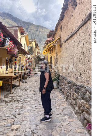 Woman walking in historic cobblestone street of Ollantaytambo. UGC 141299111