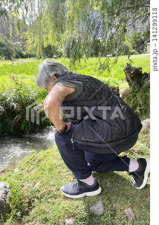 Woman standing by ancient Inca irrigation canal 141299118