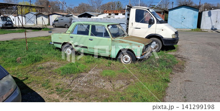Old green sedan and white van parked in residential parking lot. Old green sedan and white van parked in residential parking lot. 141299198