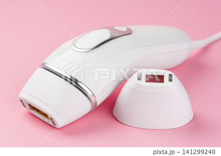 Modern white IPL photoepilator and attachment precision attachment on pink background Modern white IPL photoepilator and attachment precision attachment on pink background 141299240