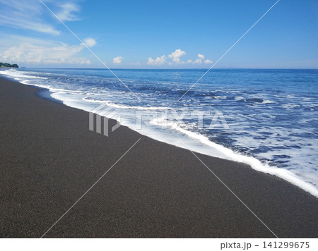 Ocean waves on a deserted beach with black volcanic sand. 141299675