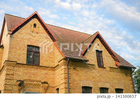 Old brick house with red tiled roof under blue sky Old brick house with red tiled roof under blue sky 141300657