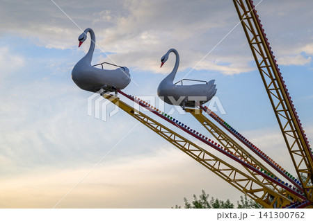 Swan-shaped ride glides against twilight sky Swan-shaped ride glides against twilight sky 141300762