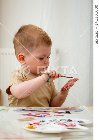 Child mixing watercolors with fingers on paper. Tactile learning about color blending. Sensory play strengthens neural connections. Art therapy and artistic development Child mixing watercolors with fingers on paper. Tactile learning about color blending. Sensory play strengthens neural connections. Art therapy and artistic development 141301000