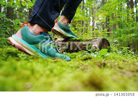 Hiking in sports shoes in forest trail. Sports sneakers for cross-country running. 141301058