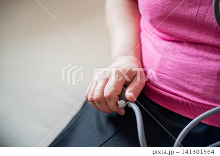 Close-up of a person using a blood pressure monitor at home. Cardiovascular health and personal health monitoring with medical equipment Close-up of a person using a blood pressure monitor at home. Cardiovascular health and personal health monitoring with medical equipment 141301564