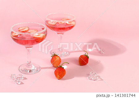 Festive alcoholic cocktail, pink martini in glasses on a bright background with strawberries, summer bar concept, alcoholic drinks at a party, restaurant and cafe advertising, modern still life Festive alcoholic cocktail, pink martini in glasses on a bright background with strawberries, summer bar concept, alcoholic drinks at a party, restaurant and cafe advertising, modern still life 141301744