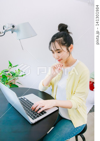 自宅でパソコンを使って仕事をする若い女性 自宅でパソコンを使って仕事をする若い女性 141301984