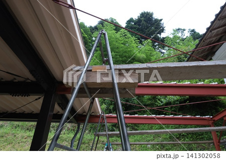 竹林を背景に赤い鉄骨フレームと脚立を見上げた低アングル工事現場 竹林を背景に赤い鉄骨フレームと脚立を見上げた低アングル工事現場 141302058
