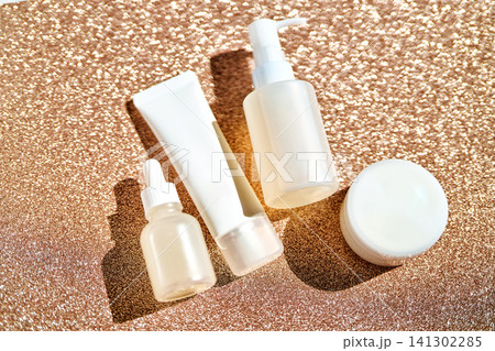 White cosmetic bottles and jars on gold glitter 141302285