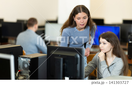 During computer lesson, female teacher helps girl student complete difficult task 141303727