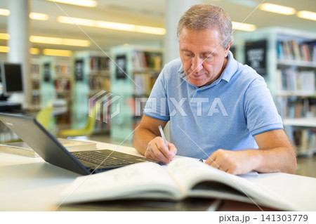 Elder male doing research on project in the city library Elder male doing research on project in the city library 141303779