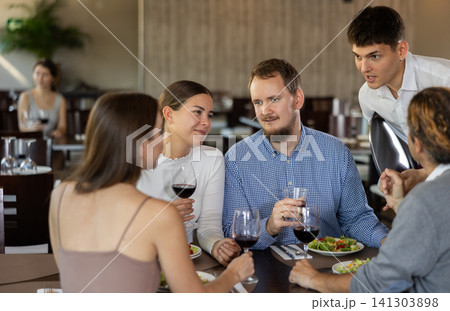 Helpful young waiter taking order from two couples in restaurant 141303898