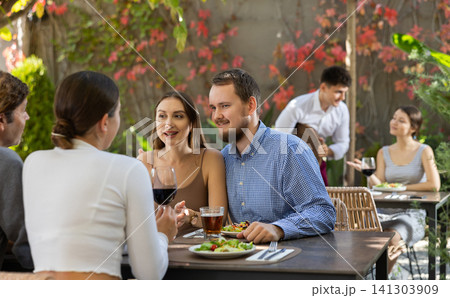 Couples of women and men eating and talking in restaurant 141303909