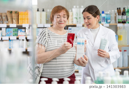Woman buyer scans cream qr code with woman pharmacist 141303983