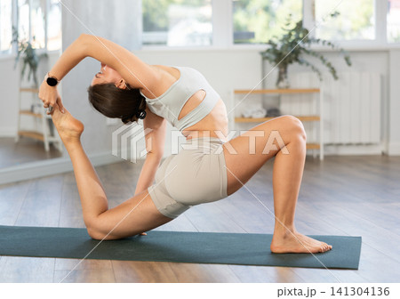 Lover of active lifestyle on yoga mat perform doing Anjaneyasana in gym Lover of active lifestyle on yoga mat perform doing Anjaneyasana in gym 141304136