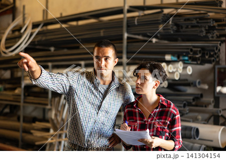 Man and woman together carry out accounting and inventory in a building materials warehouse Man and woman together carry out accounting and inventory in a building materials warehouse 141304154