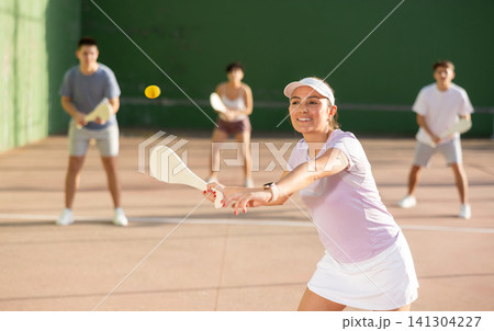 Sporty woman performing basic strokes during paleta fronton group training 141304227