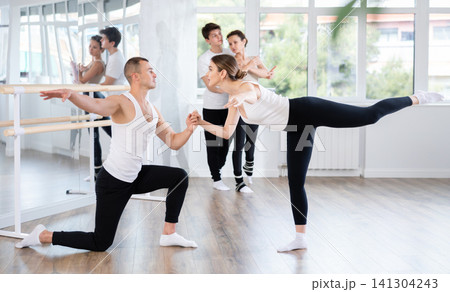 Graceful couple of ballet dancers performing supports at group class 141304243