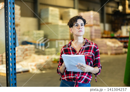 Female storekeeper checks presence of goods in the building materials warehouse Female storekeeper checks presence of goods in the building materials warehouse 141304257