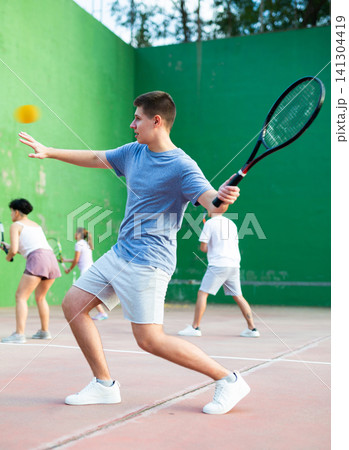 Young man serving ball during frontenis game outdoors Young man serving ball during frontenis game outdoors 141304419