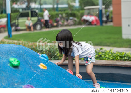 Asian Little Girl Climbing Wall at Outdoor Playground 141304540