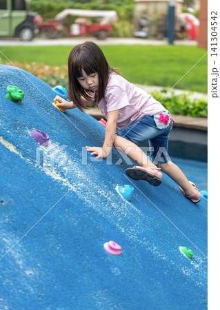 Asian Little Girl Climbing Wall at Outdoor Playground Asian Little Girl Climbing Wall at Outdoor Playground 141304542