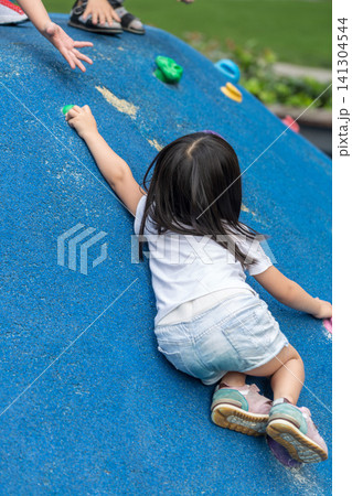 Asian Little Girl Climbing Wall at Outdoor Playground 141304544