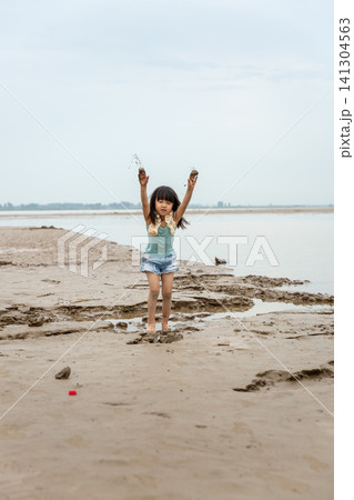 Asian Little Girl Playing with Mud and Water by Riverside 141304563