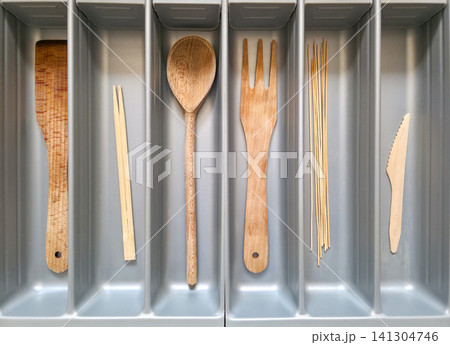 Wood and bamboo spoon, fork, chopsticks and skewers neatly sorted in a drawer organizer. Concept of zero waste, plastic-free kitchen, and sustainable swaps 141304746