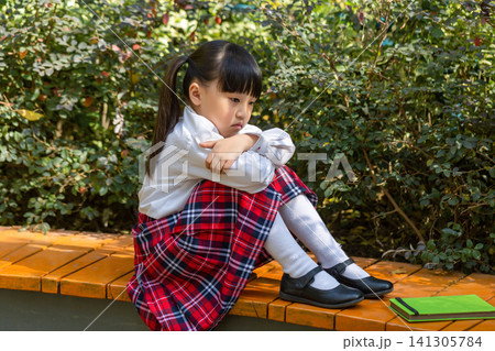 Sad Asian little girl sitting alone in park, childhood loneliness and emotional problem concept Sad Asian little girl sitting alone in park, childhood loneliness and emotional problem concept 141305784