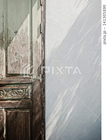 Rustic Old Wooden Door with Peeling Mint Green Paint and Soft Leaf Shadow on White Wall Background Rustic Old Wooden Door with Peeling Mint Green Paint and Soft Leaf Shadow on White Wall Background 141305890