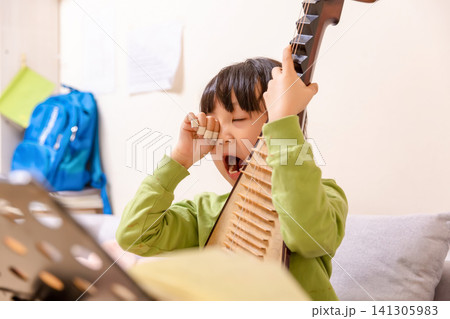 A tired Chinese girl yawns wearily as she practices the pipa at home. A tired Chinese girl yawns wearily as she practices the pipa at home. 141305983