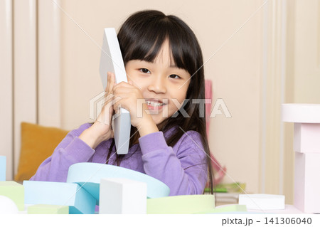 An Asian girl playing with foam blocks indoors. 141306040