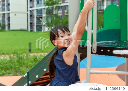 Happy Asian little girl playing on playground equipment, active childhood and outdoor fun concept 141306140