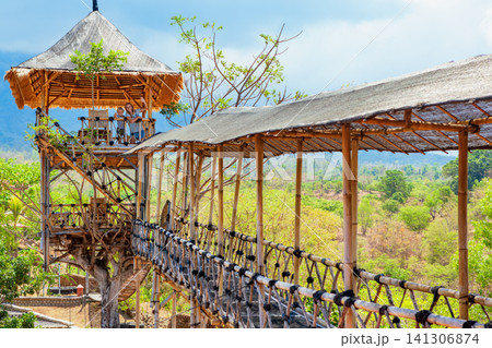 Happy family in bamboo treehouse with rooftop lookout and hanging bridge in Tulamben, Bali. Surrounded by lush tropical greenery and mountains, perfect for eco-tourism and adventure travel photography Happy family in bamboo treehouse with rooftop lookout and hanging bridge in Tulamben, Bali. Surrounded by lush tropical greenery and mountains, perfect for eco-tourism and adventure travel photography 141306874