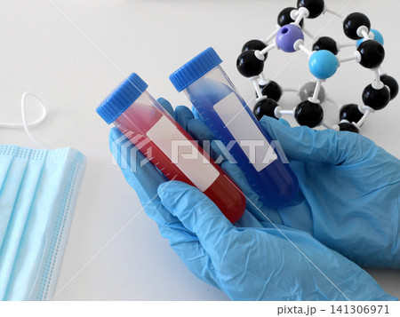 Gloved hand holding laboratory sample tubes near molecular model and protective mask for chemistry studies, virus diagnostics and medical research concepts. Lab scene, chemistry education concept Gloved hand holding laboratory sample tubes near molecular model and protective mask for chemistry studies, virus diagnostics and medical research concepts. Lab scene, chemistry education concept 141306971