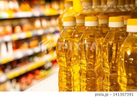 Clear Plastic Bottles of Edible Oil on a Grocery Store Shelf Surrounded by Colorful Products and Items in a Retail Environment Clear Plastic Bottles of Edible Oil on a Grocery Store Shelf Surrounded by Colorful Products and Items in a Retail Environment 141307391