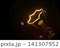 glowing star filament incandescent light bulb illuminated against a dark background. The warm light and vintage filament design create dramatic visual representing innovation, creativity, inspiration 141307952