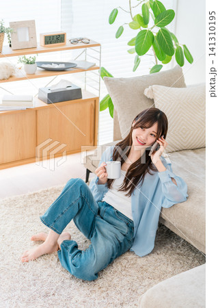 ソファの前に座ってスマホで通話するお洒落な女性 141310195