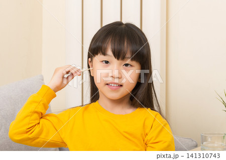 Asian girl cleaning ear with cotton swab child hygiene healthcare concept Asian girl cleaning ear with cotton swab child hygiene healthcare concept 141310743