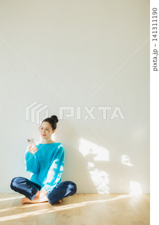 床に座ってスマホを見る若い女性 床に座ってスマホを見る若い女性 141311190