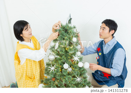 クリスマスツリーに飾り付けをする男女 クリスマスツリーに飾り付けをする男女 141311278