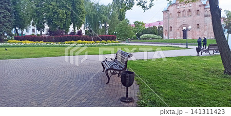 Cozy park alley with benches near ancient Pyatnytska church in Chernihiv Cozy park alley with benches near ancient Pyatnytska church in Chernihiv 141311423