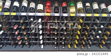 Various wine bottles with colorful labels displayed on a metal store rack Various wine bottles with colorful labels displayed on a metal store rack 141311445