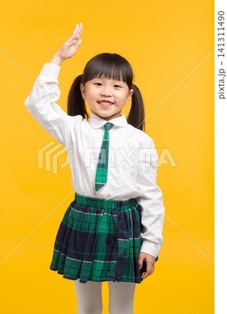 Happy Asian school girl raising hand in class on yellow background, confident student answering question, education concept Happy Asian school girl raising hand in class on yellow background, confident student answering question, education concept 141311490