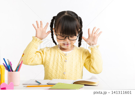 Asian schoolgirl showing various emotions while doing homework, feeling confused, inspired, and excited. Asian schoolgirl showing various emotions while doing homework, feeling confused, inspired, and excited. 141311601