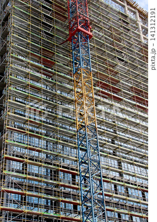 Close up of a construction crane and metal scaffolding on modern building Close up of a construction crane and metal scaffolding on modern building 141312191